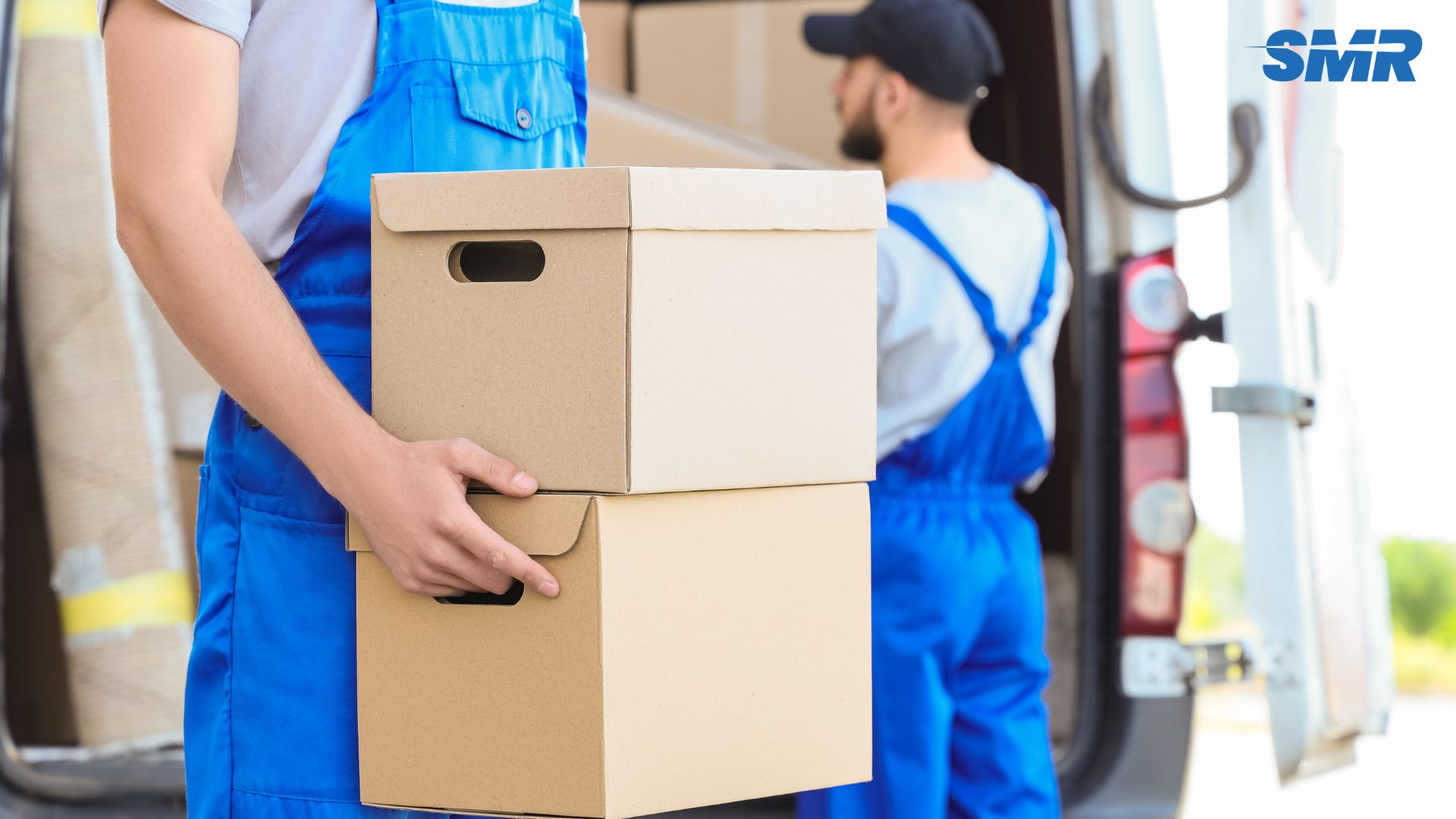 A professional removals van with uniformed movers loading boxes outside a residential property in Chiswick.