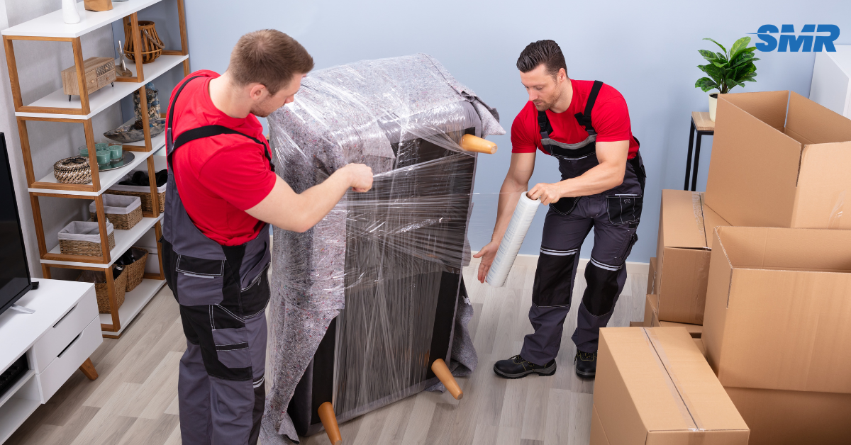 Two movers carrying a sofa into a house during a Kidbrooke move.