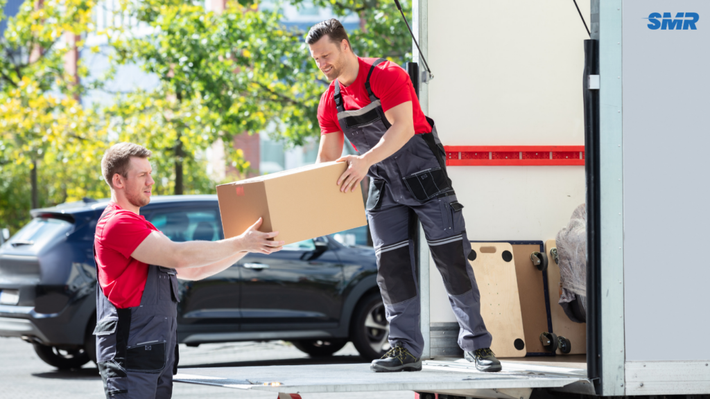 Movers carrying office furniture and computers